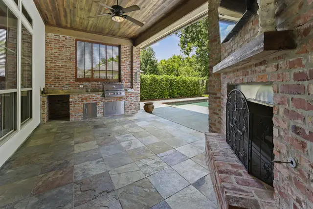 Covered outdoor living area with fireplace and built-in grill